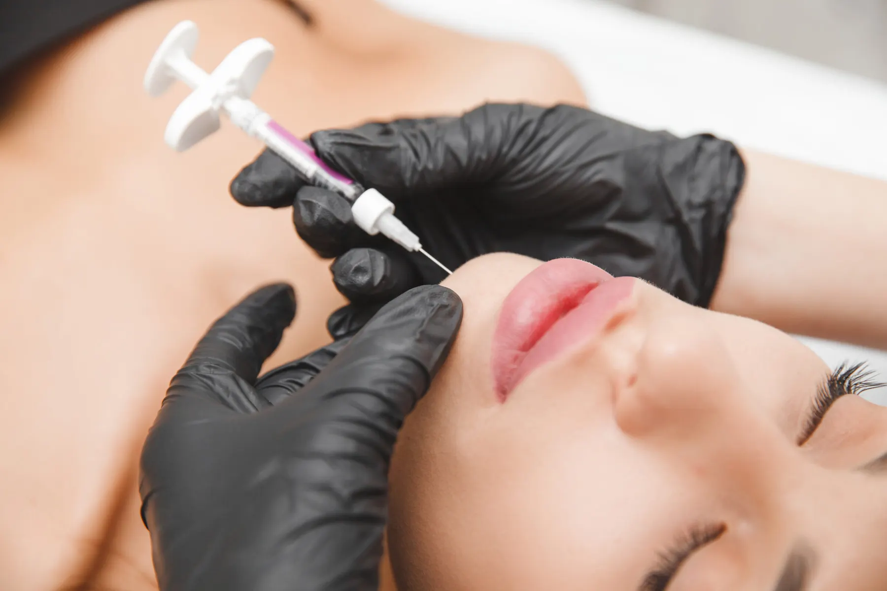 A clinician administering fat dissolving injections beneath a client's chin