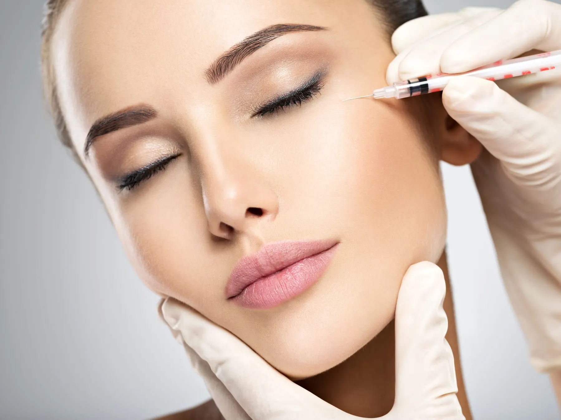 A nurse injector placing hyaluronic acid filler into a client's cheek