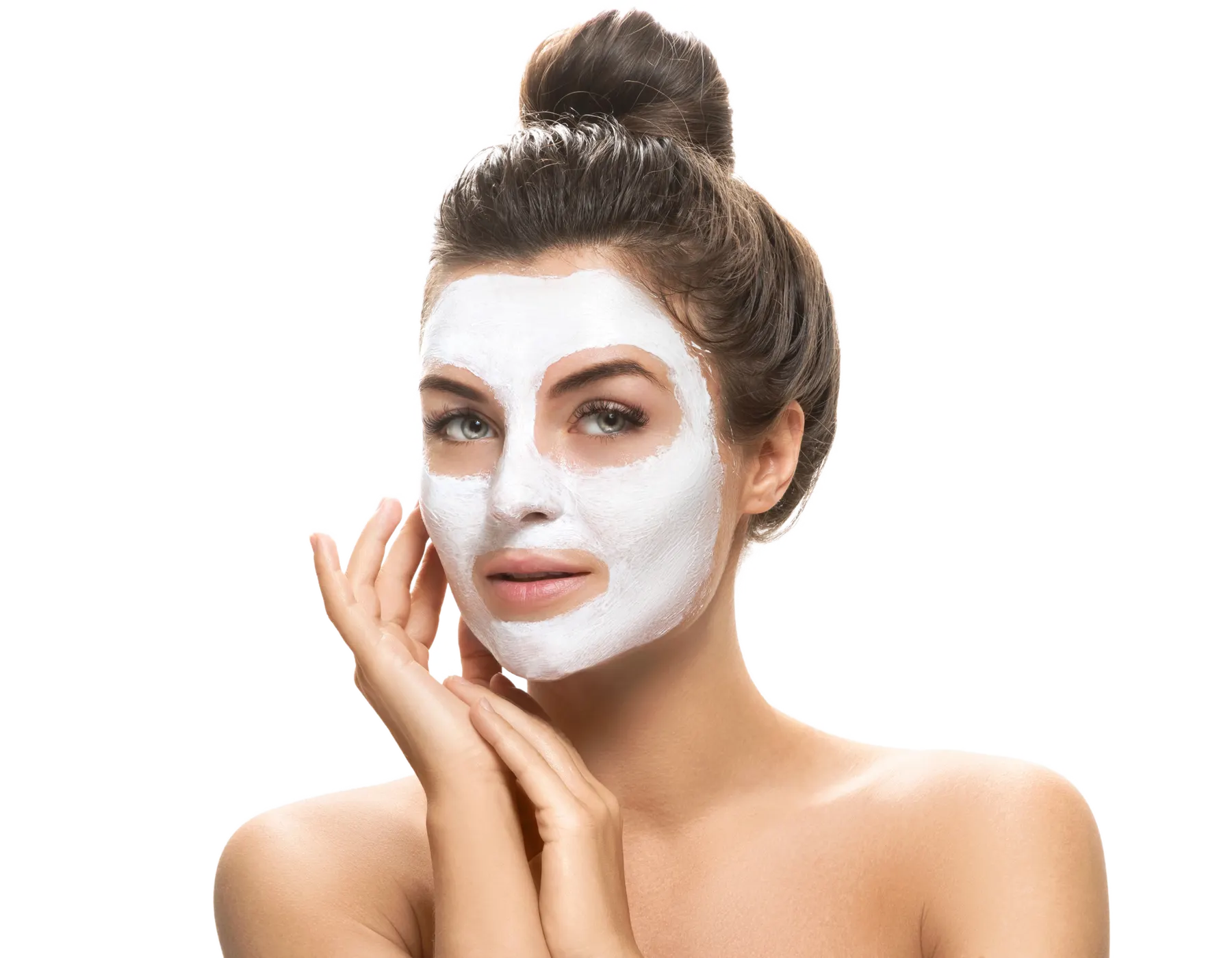 A woman with a white clay treatment mask spread across her face, hands resting at her cheek