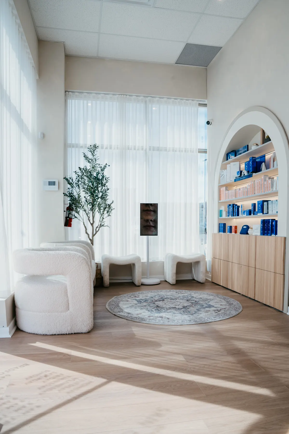 The waiting area at Bradford Skin Clinic, with seating, an olive tree and arched retail shelving