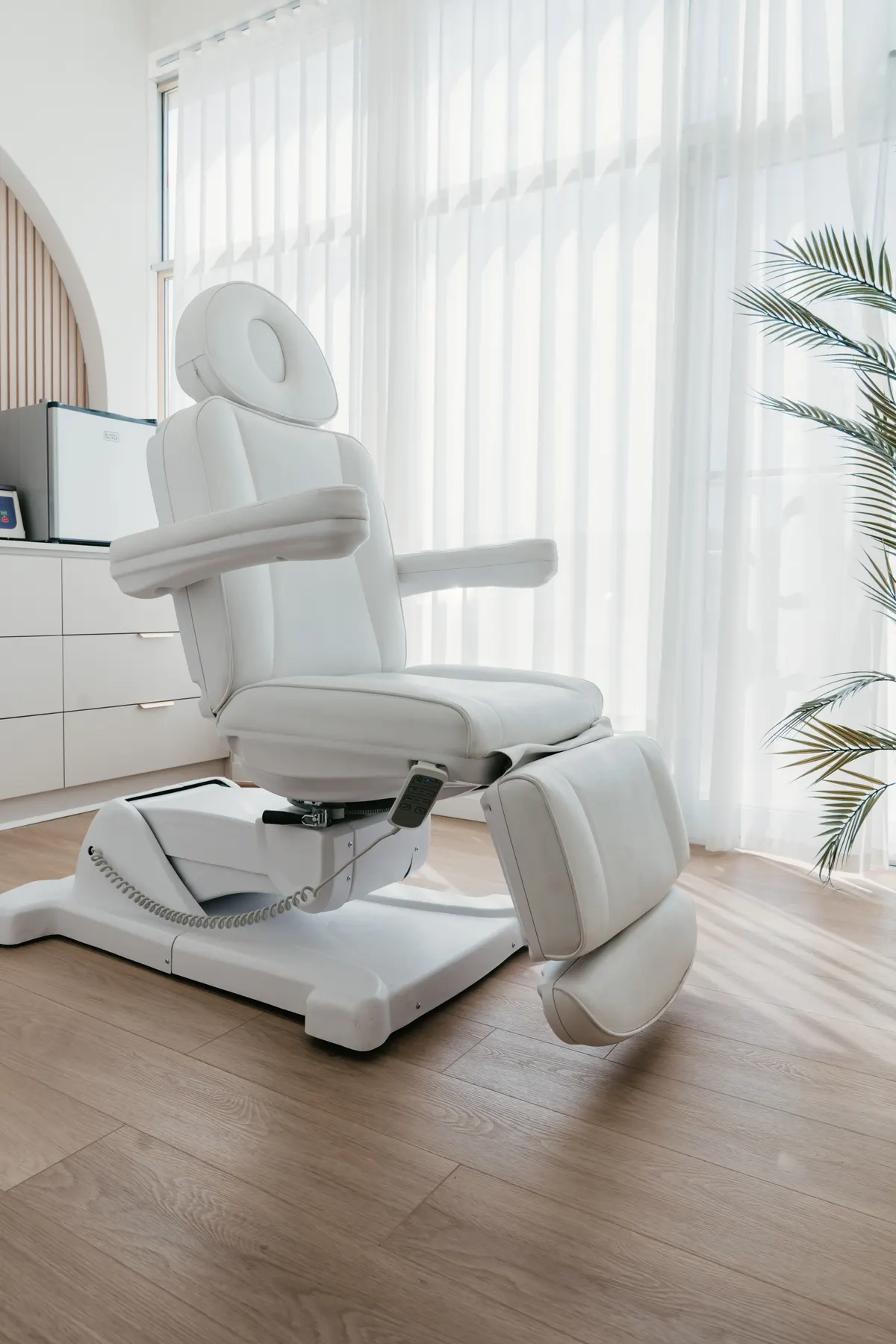 A white reclining treatment chair in a bright Bradford Skin Clinic treatment room