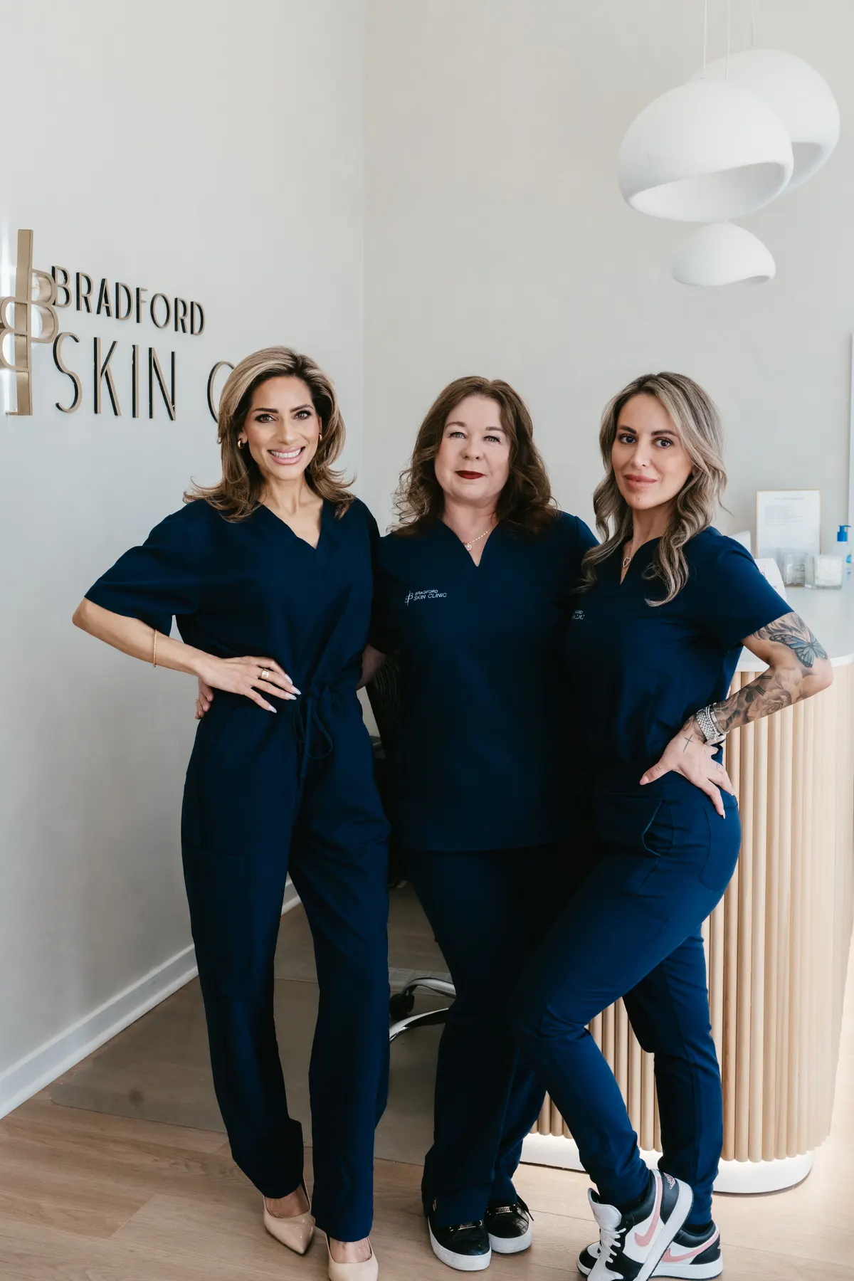 Three members of the Bradford Skin Clinic team in navy clinic scrubs