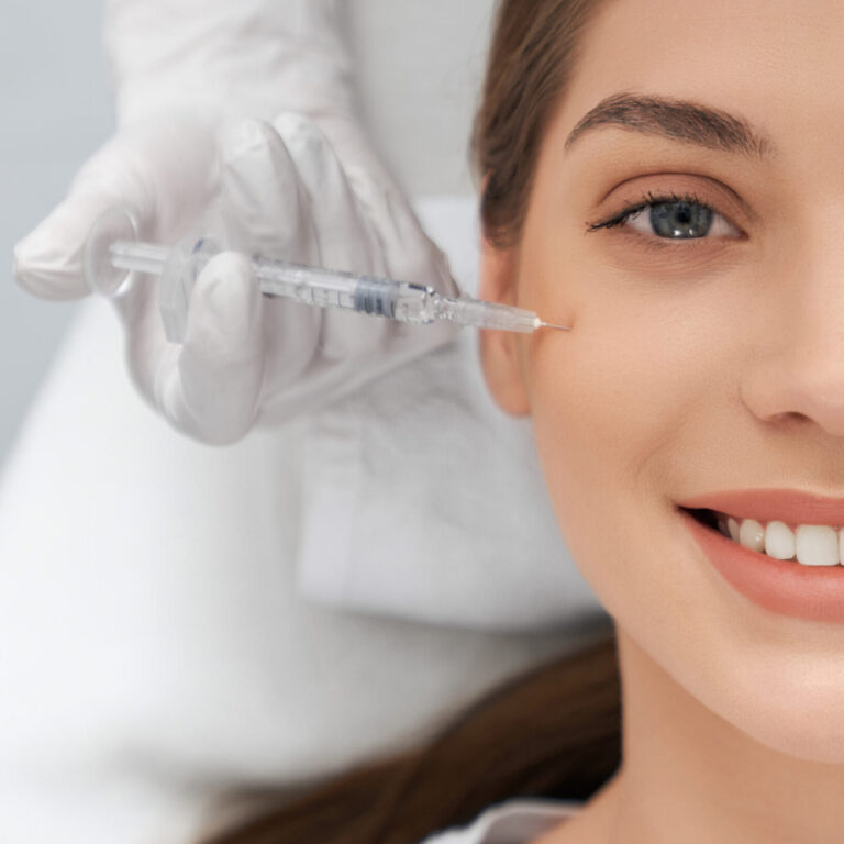 Close up portrait of smiling brunette beautiful woman on procedure injection anti-aging skin in beautician. Concept of process injection for improve the condition face.